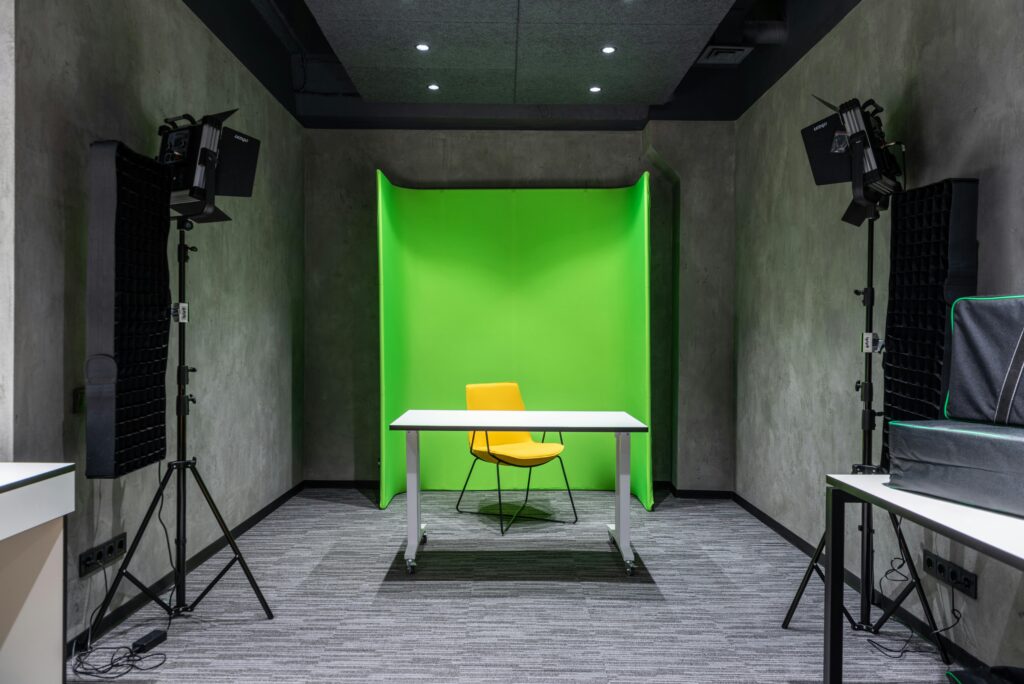 Bright and spacious studio setup with green screen backdrop and yellow chair centered.
